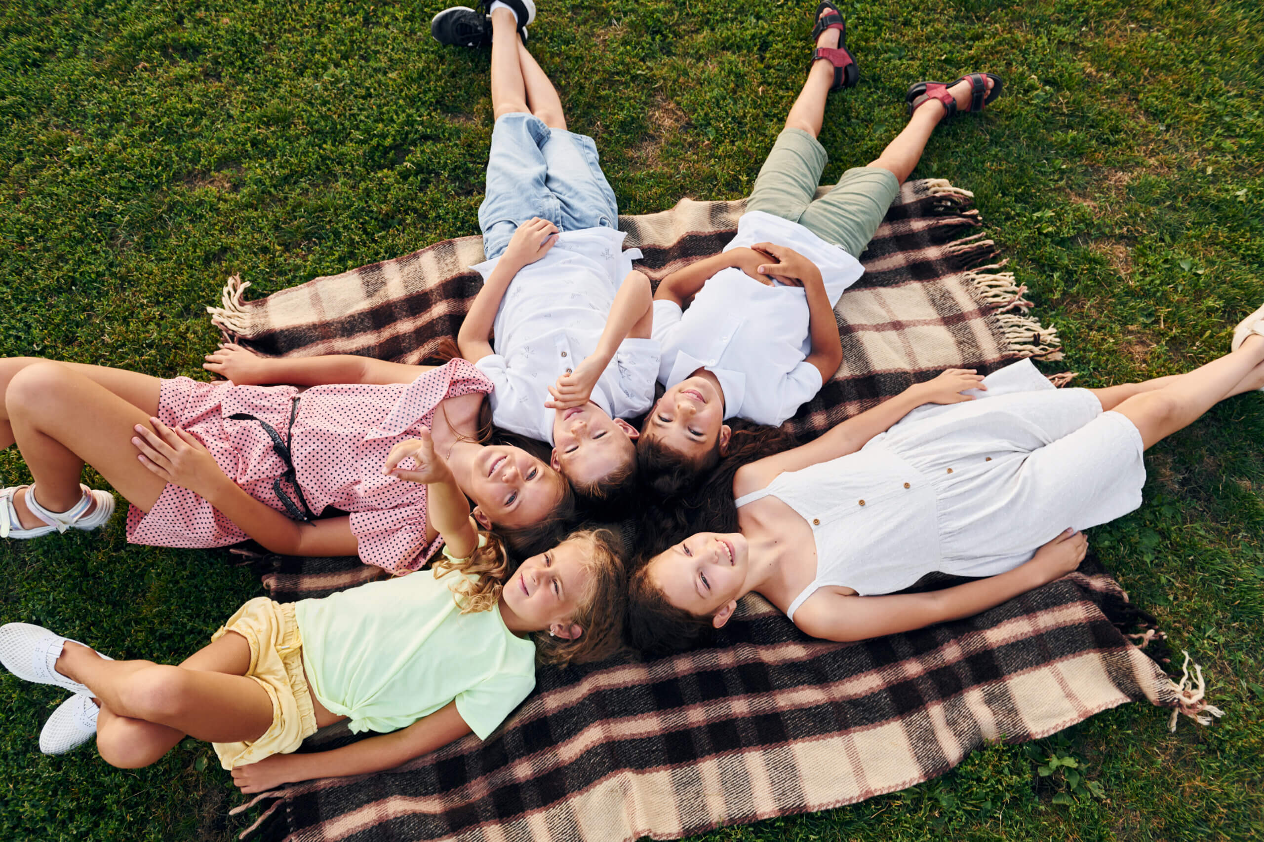 Having a rest and laying down. Group of happy kids is outdoors on the sportive field at daytime